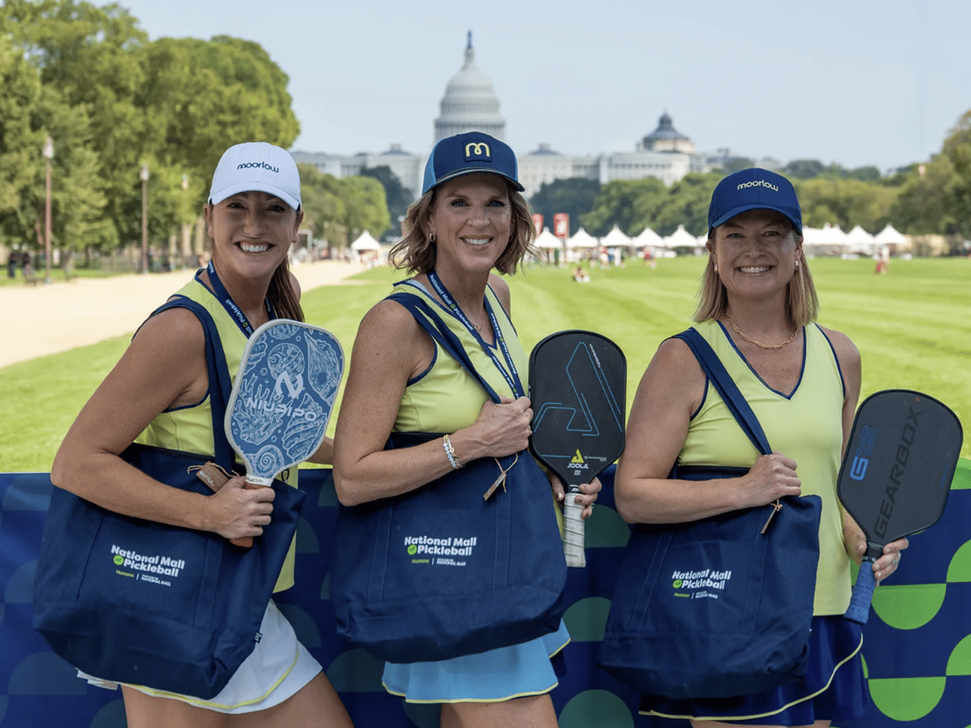 Three women posing with pickleball paddles