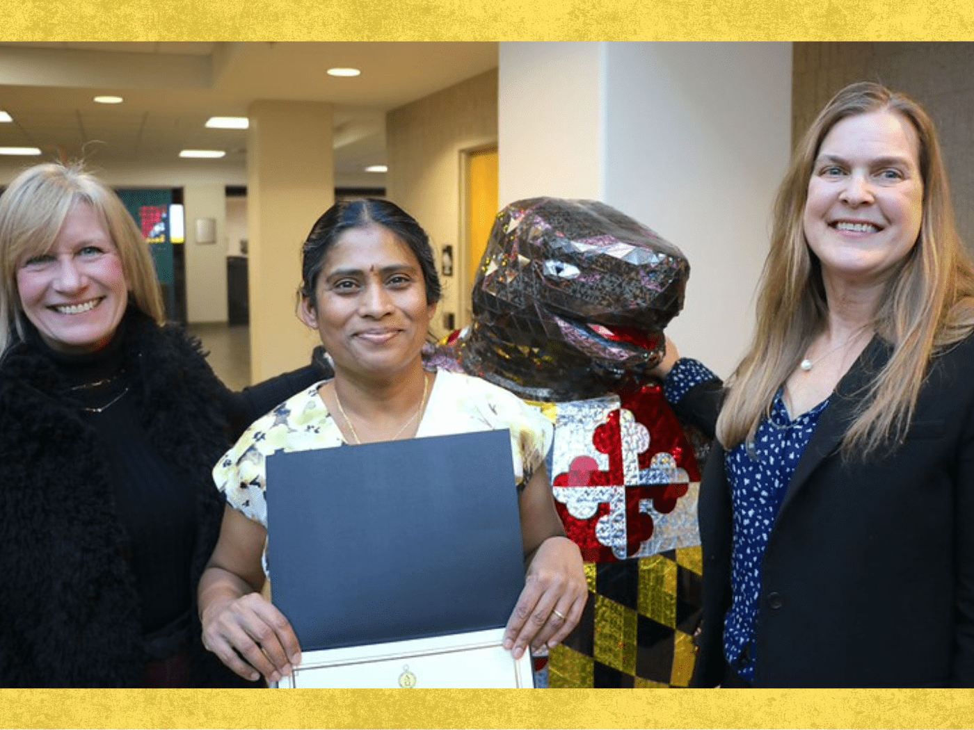 Two professors and one graduate student pose together in front of metallic terrapin mascot
