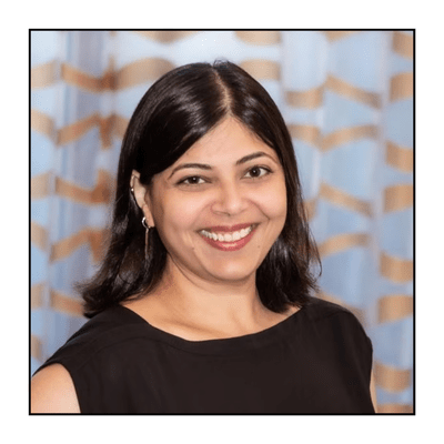 Female professor with dark hair and eyes smiles to camera, wearing black sleeveless top