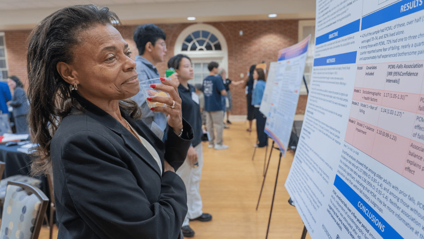older black woman smiles as she reads a research poster