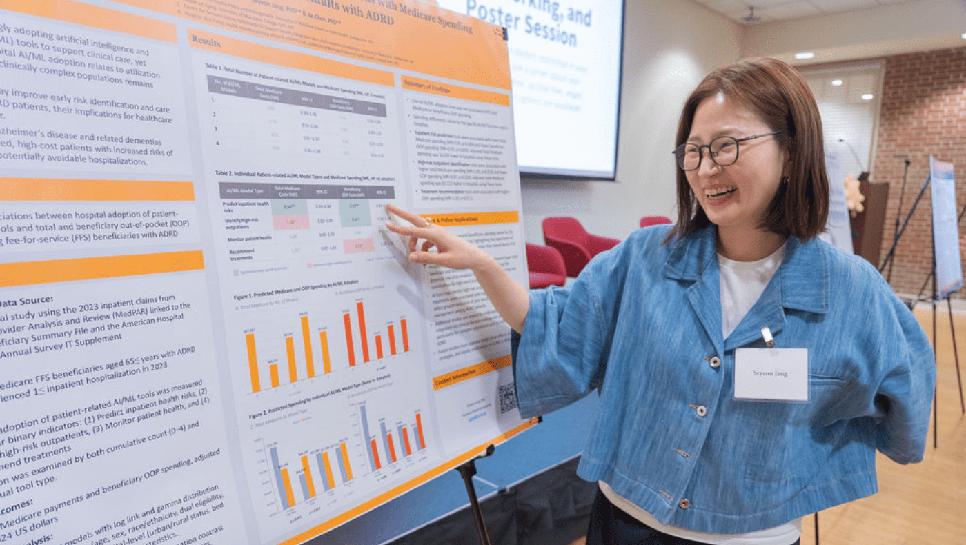 Asian female student in denim top laughs while pointing at data on a research poster to her right