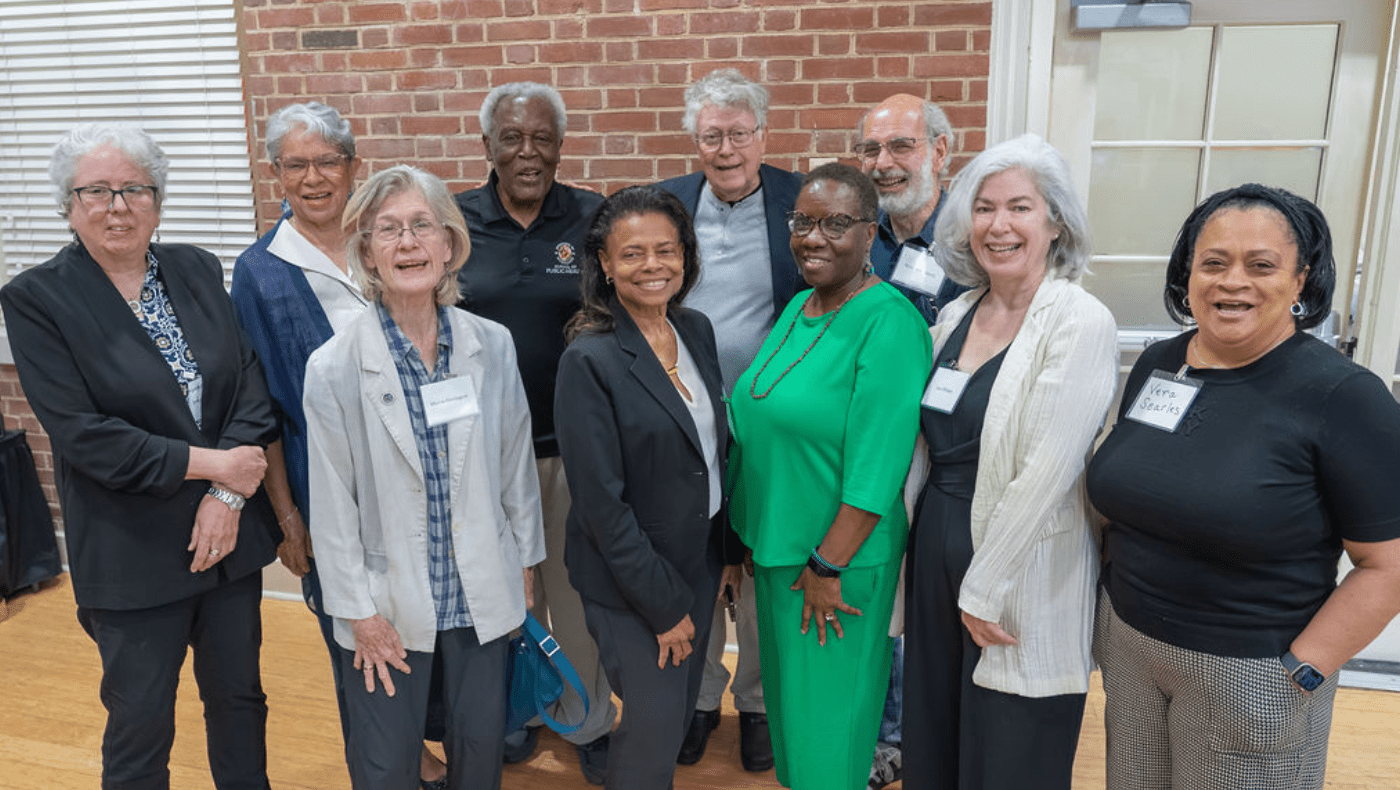 Group of elders pose for the camera at a conference, with brick wall in background