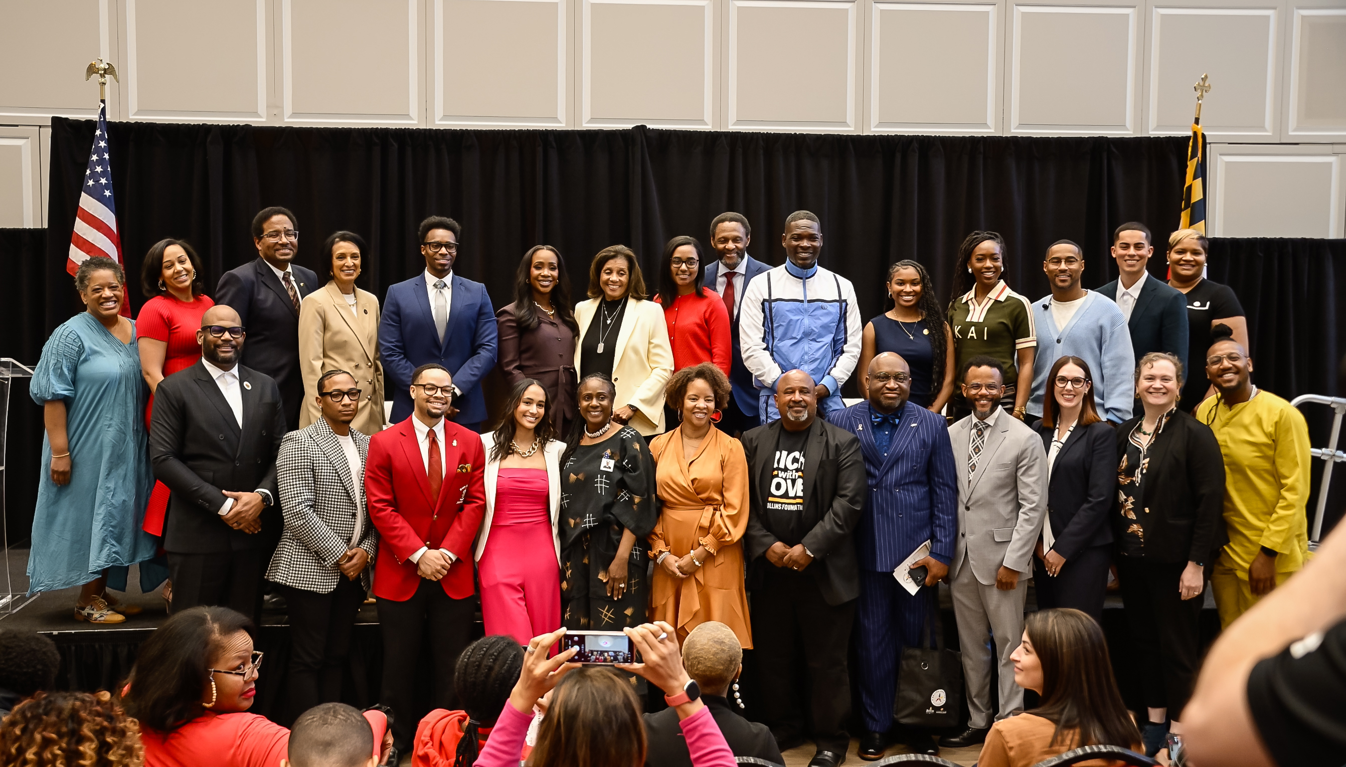 Large group of people stand on stage posing for camera