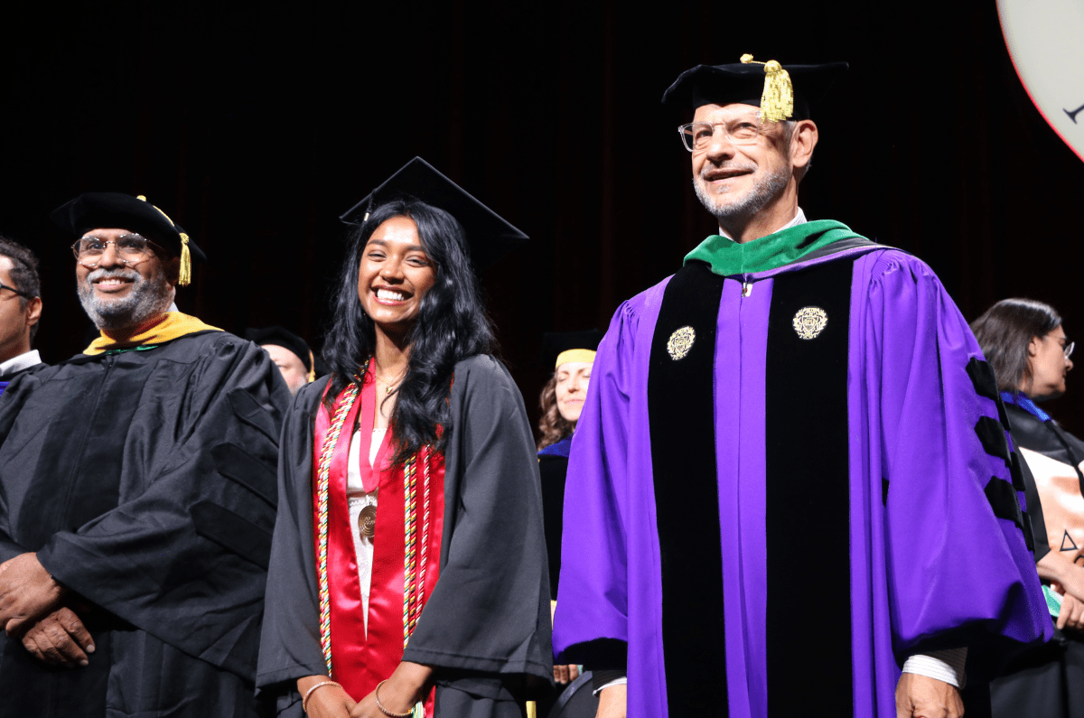 commencement speaker, student speaker and dean of the college posing on the commencement stage smiling