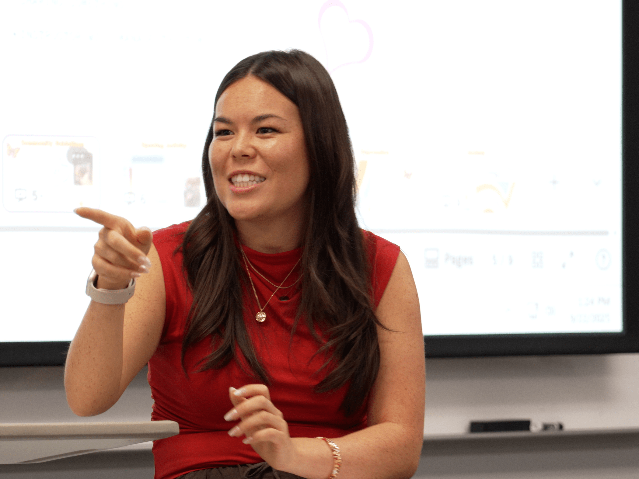 Woman with long brown hair and red sleeveless top instructing a class