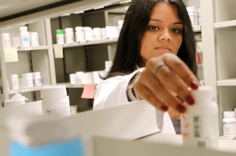 student pharmacist grabbing a pill bottle off the shelf